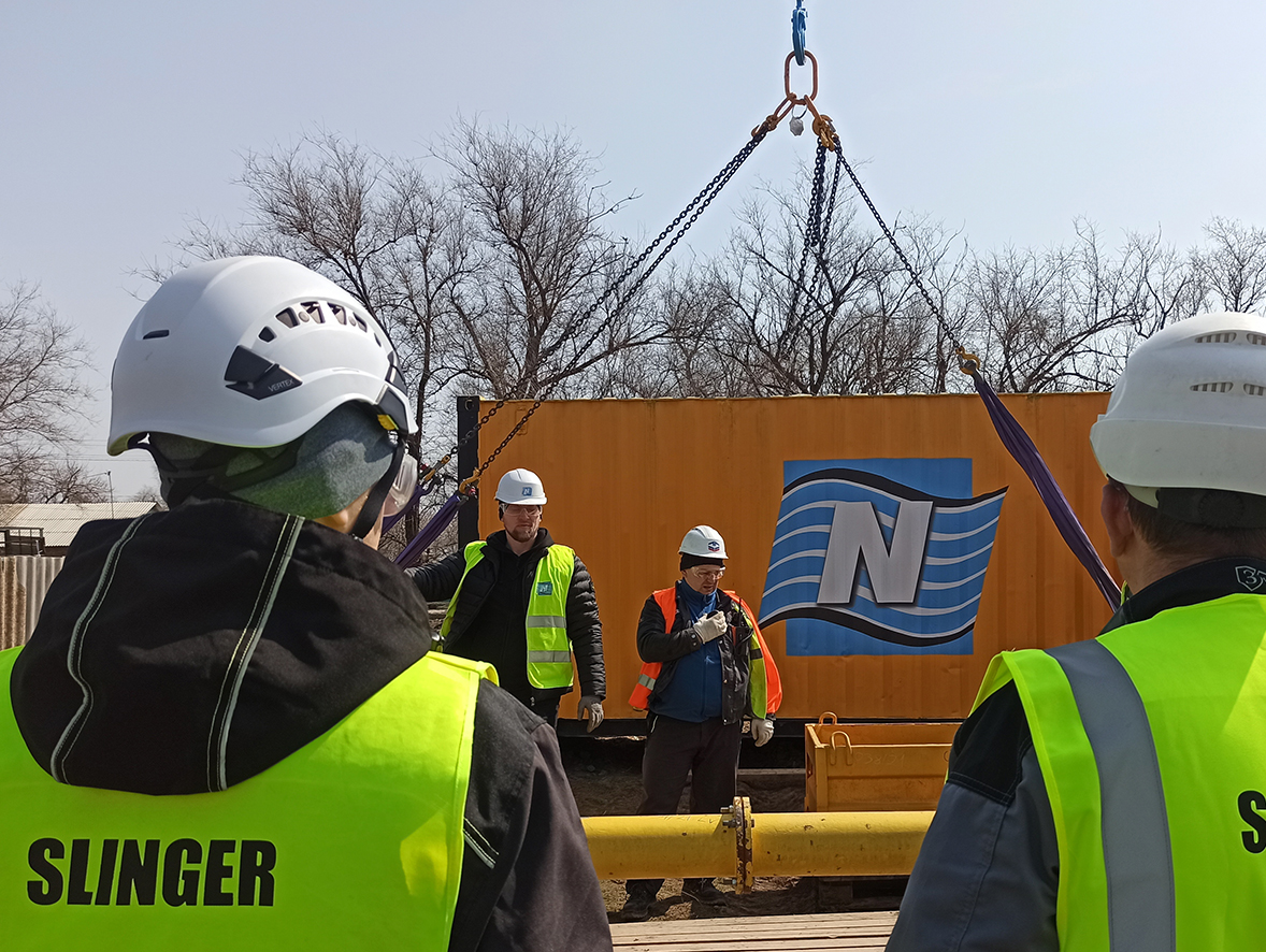 Two slinger construction workers in front of a crane lift