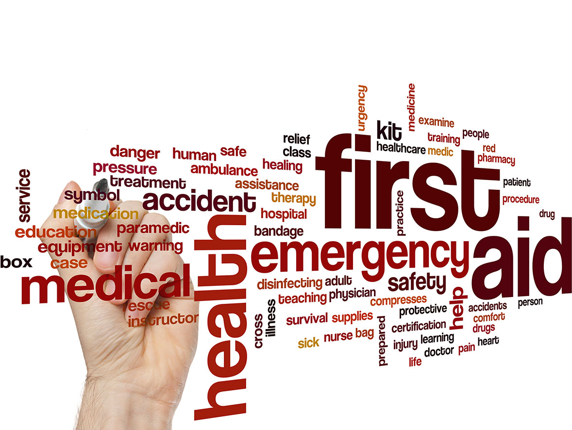 A hand writing on a word board which contains terms relating to first aid such as emergency or health